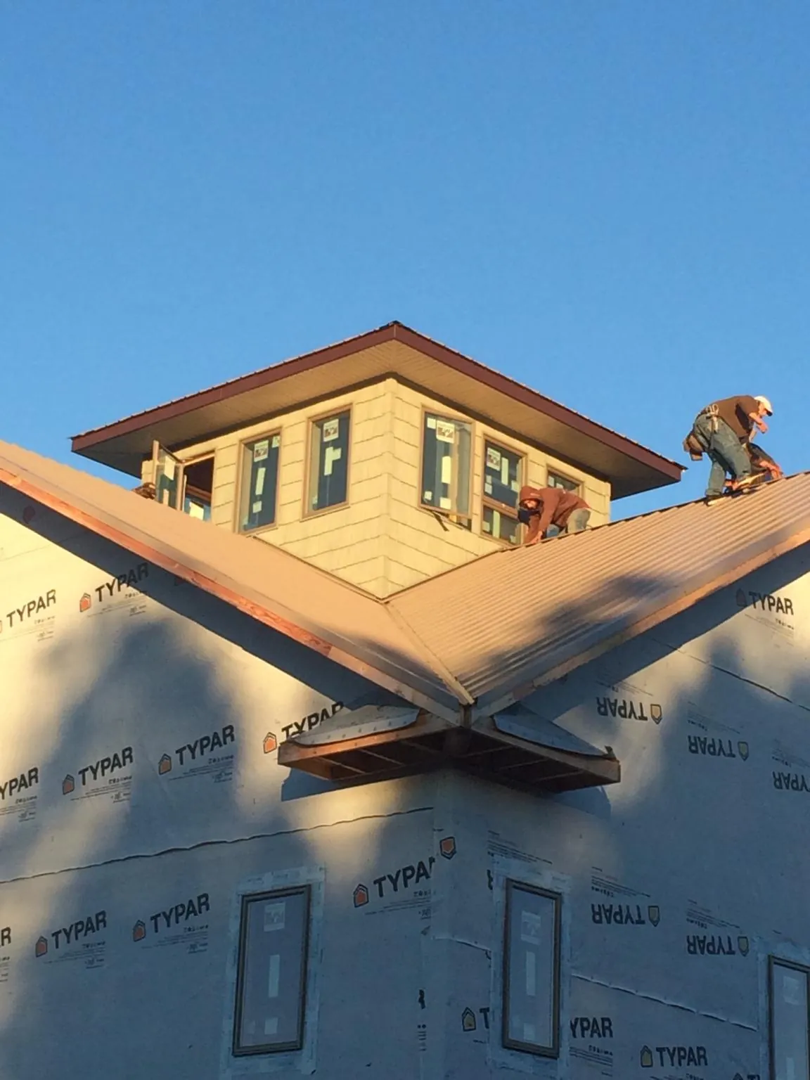 Roofers working around a rooftop cupola on a new metal roof at sunset — Roof Waterproofing in Seagrove by Roofing Brothers